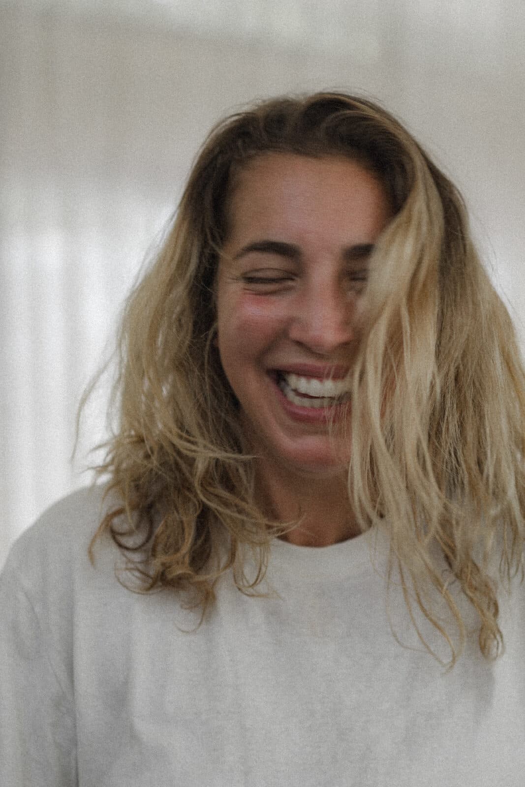 The founder of The Wolf Wisdom, laughing with eyes closed, hair falling across the face